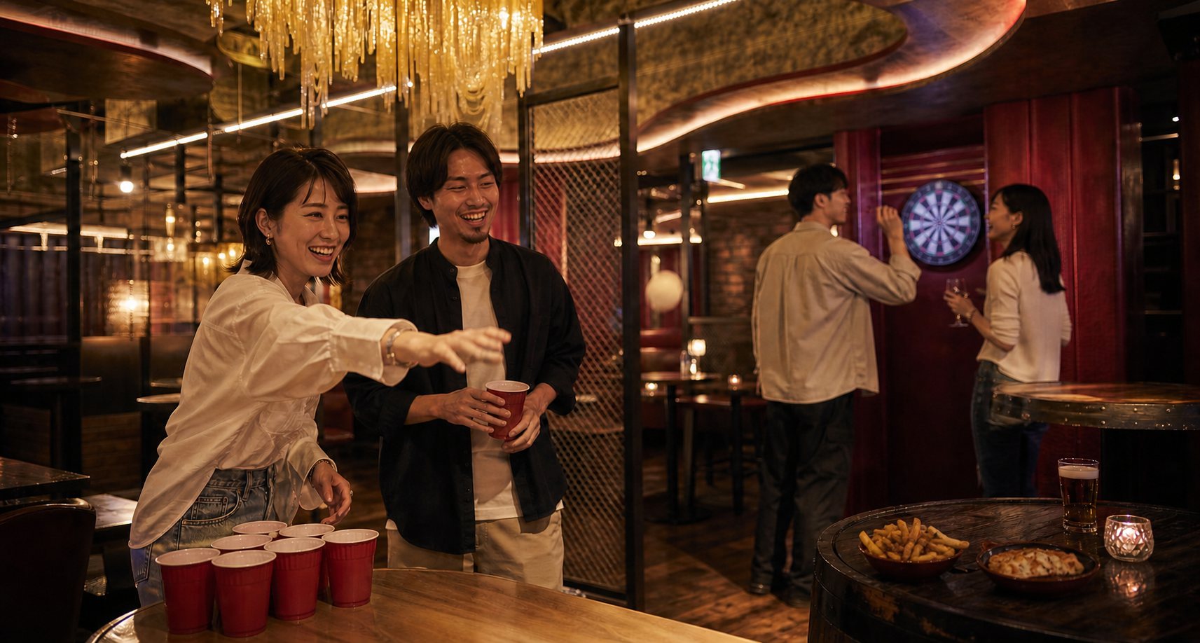 軽食をつまみながらダーツやゲームを楽しむ男女